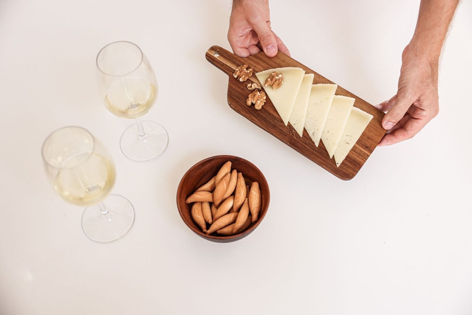 Lagrad hårdost med valnötter, kex och vitt vin på serveringsbord